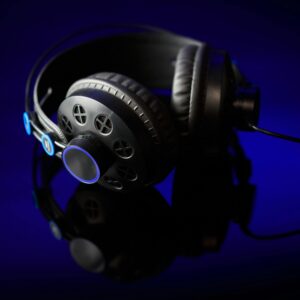 Stylish black headphones with glowing accents on a reflective surface against a dark backdrop.