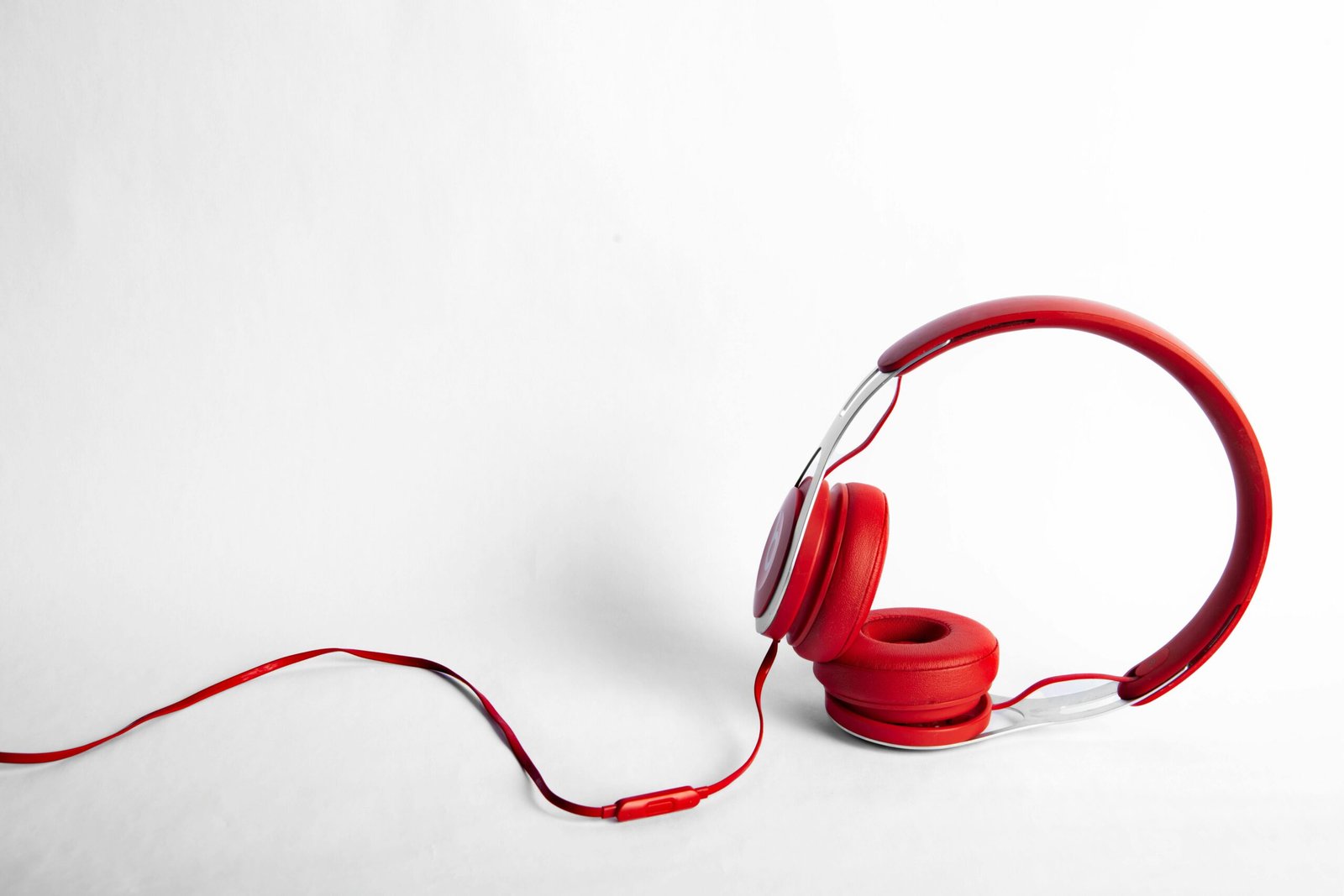 Stylish red over-ear headphones with long cable against a white background.